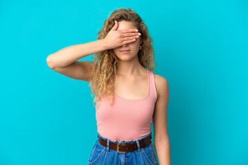 Young blonde woman isolated on blue background covering eyes by hands. Do not want to see something