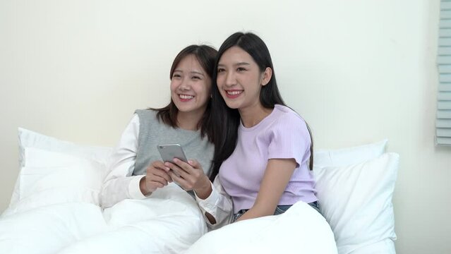 girl holding smart phone social online with her couple losbian, Asian woman Lesbian in love on the bed. Couple losbian Sex LGBT and lifestyle concept.