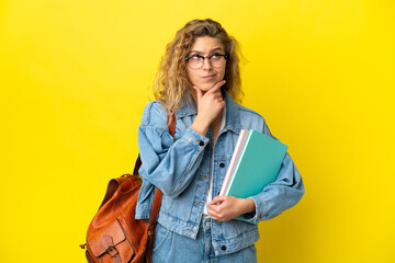 Young student caucasian woman isolated on yellow background having doubts