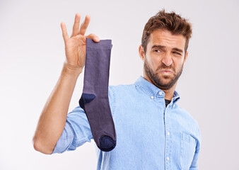 This isnt going anywhere near to my feet. Studio shot of a handsome young man holding an unpleasant...