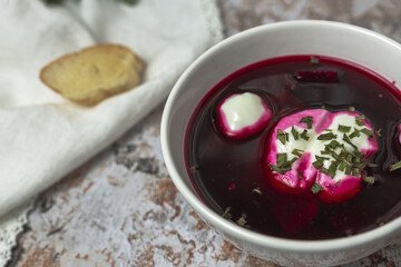 Traditional Ukrainian and Russian national red borscht soup en bol with sour cream and herbs