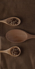 three wooden spoons with beniseed and linseed isolated on canvas background