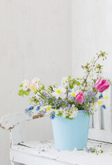 Fototapeta na wymiar spring flowers in vintage white interior with old wooden bench