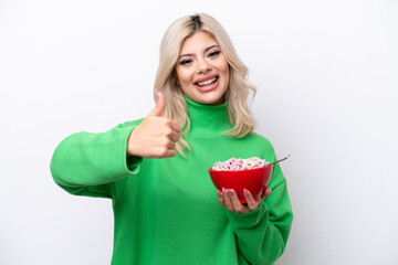 Young Russian woman holding a bowl of cereals isolated on white background with thumbs up because something good has happened