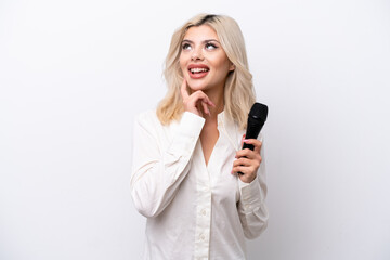 Young singer woman picking up a microphone isolated on white background thinking an idea while looking up