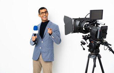 Reporter African American man holding a microphone and reporting news over isolated white background pointing to the front and smiling