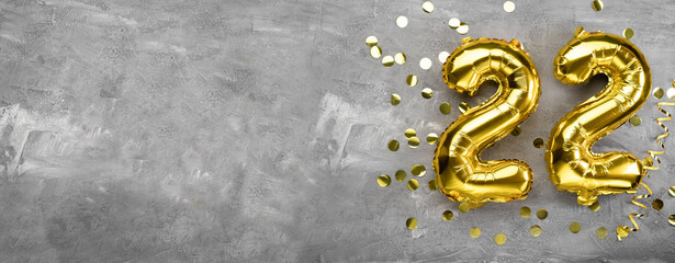Yellow foil balloon number, number twenty two on a concrete background. Birthday card with inscription 22. Anniversary concept. for anniversary, birthday, new year celebration. banner,