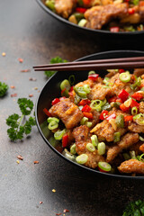 Stir fry salt and pepper pork loin with herbs in black bowl. Asian food