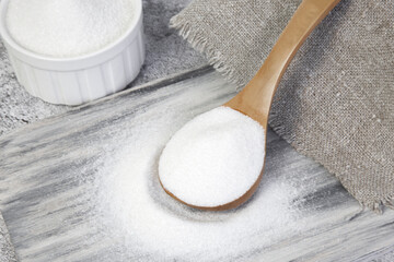 White refined sugar in a wooden spoon. The concept of harmful unhealthy food. Glucose and diabetes mellitus. Sugar deficiency