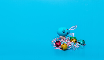blue Easter egg with ears and colored quail eggs