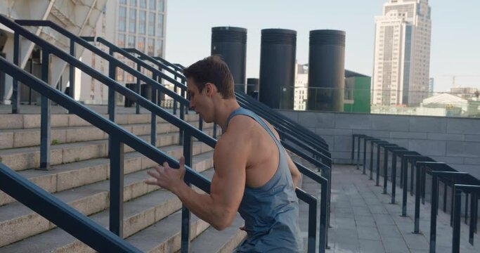 young man athlete running up stairs training intense cardio workout exercise male runner jogging on steps in urban city background