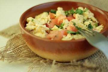 Soft creamy scrambled eggs in cast iron skillet and cherry tomatoes. Selective focus, space for text.