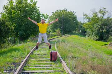 in a yellow jacket, a tourist with a suitcase jumps on the railroad