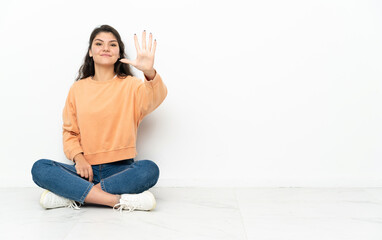 Teenager Russian girl sitting on the floor counting five with fingers