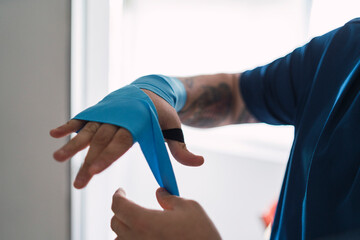 persona poni&eacute;ndose bandas azules en la mano, persona prepar&aacute;ndose para hacer deporte