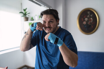 hombre con tatuajes usando guantes para hacer deporte en el salón con flores de fondo