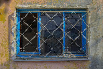 an old window with a colored wall and iron railings