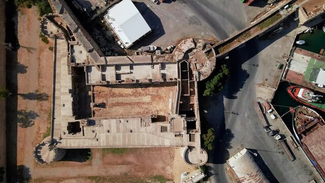 Aerial 4k Othello Castle medieval building in Famagusta Walled City in North Cyprus which is surrounded with old town streets, sea port and touristic attractions with blue sky in sunny day, Cyprus
