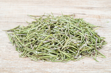 Dried rosemary spice on wooden background.