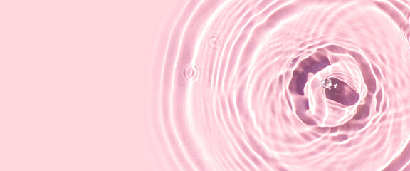 Drops on pink water background under sunlight. Top view, flat lay. Banner
