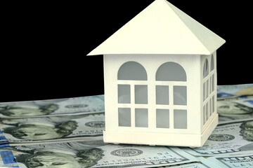 Model of small family house standing on background of dollars banknotes. Cut out. Selective focus. Isolated on black. Saving money for buying property. - 493775369