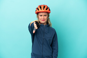 Young cyclist woman isolated on blue background showing thumb down with negative expression