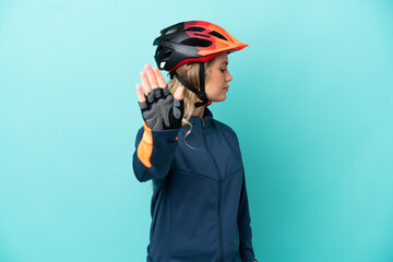 Young cyclist woman isolated on blue background making stop gesture and disappointed