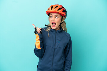 Young cyclist woman isolated on blue background intending to realizes the solution while lifting a finger up