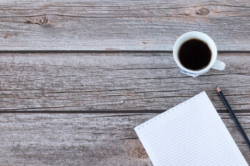 Blanck spiral notebook with pencil, and a cup of coffee on a rustic wooden table background with copy space. Top view, flat lay. 