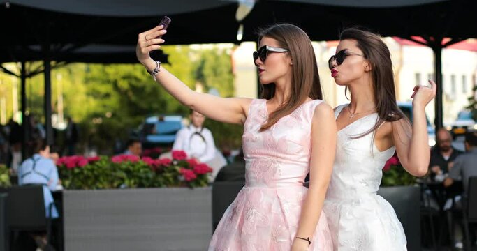 Two fashionable woman with red lips making self portrait at smart phones.
