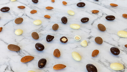 Assortment of almonds coated with chocolate scattered on a table. Mix of chocolate nut sweet snack.