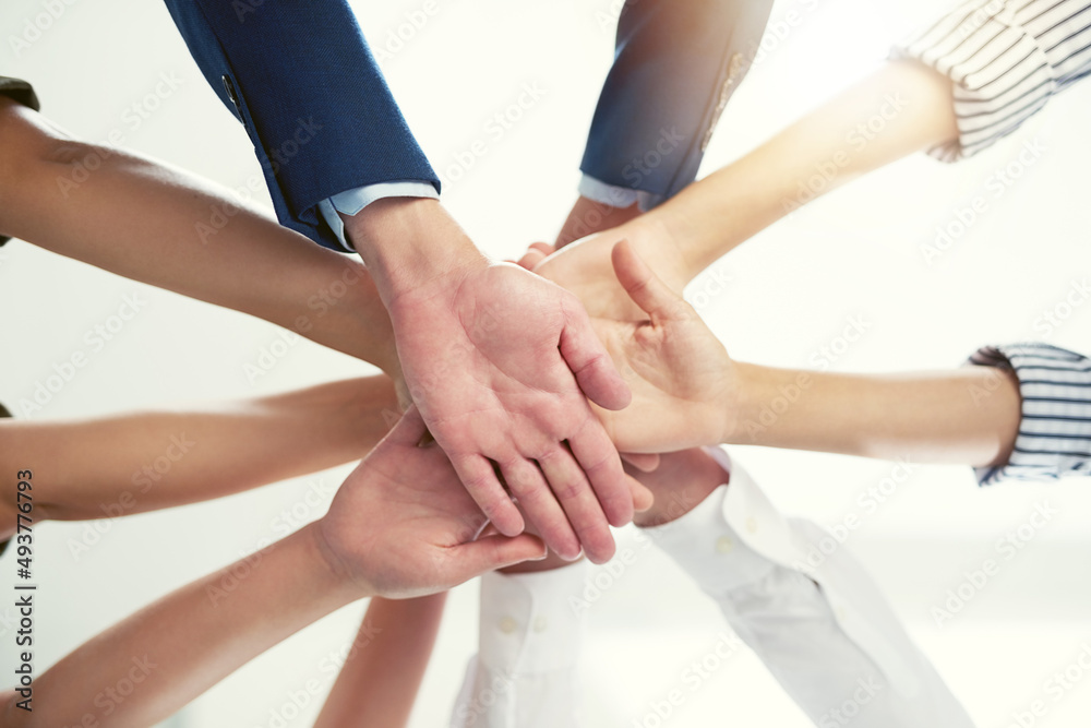Poster well conquer together. closeup shot of a group of businesspeople joining their hands together in uni