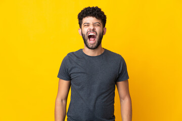 Young Moroccan man isolated on yellow background shouting to the front with mouth wide open