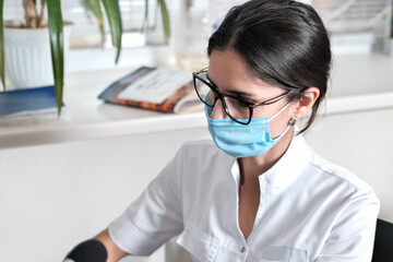 brunette woman doctor working in a hospital, working place of female asian doctor. woman wearing medical mask and doctor uniform