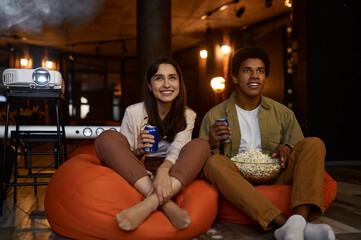 Smiling loving couple or friends watching movie