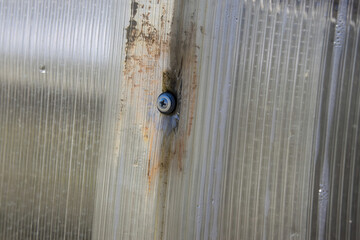 Close-up of incorrect fastening of a polycarbonate sheet. Damaged polycarbonate sheet due to...