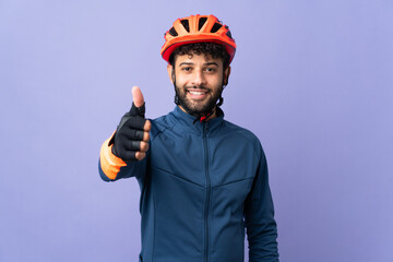 Young Moroccan cyclist man isolated on purple background with thumbs up because something good has happened - obrazy, fototapety, plakaty