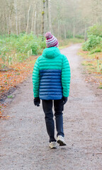 Single elderly woman walking alone in forest during lockdown for good mental and physical health