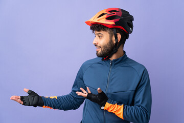 Young Moroccan cyclist man isolated on purple background with surprise expression while looking side - obrazy, fototapety, plakaty