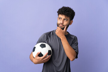 Handsome Moroccan young football player man over isolated on purple background and looking up