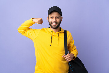 Young sport Moroccan man with sport bag isolated on purple background doing strong gesture