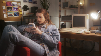 Young girl playing with a 90s portable game console in her bedroom. - obrazy, fototapety, plakaty
