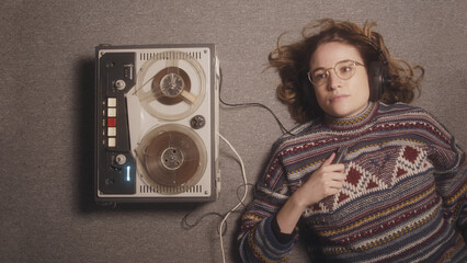 A teenage girl lying thinking on the floor next to a old tape recorder