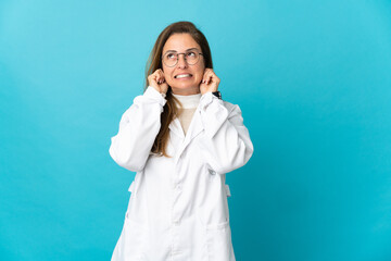 Middle age Brazilian doctor woman isolated on blue background frustrated and covering ears