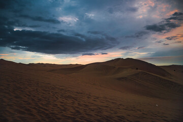 Naklejka na ściany i meble Landscape of the desert in sunset time in a cloudy day.