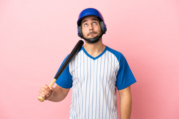 Baseball player with helmet and bat isolated on pink background and looking up