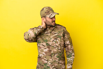 Military man isolated on yellow background with neckache