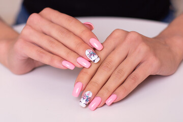 Beautiful female hands with creative manicure nails with unicorn design, pink gel polish