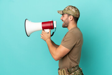 Military with dog tag over isolated on blue background shouting through a megaphone