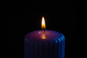 Purple candle with orange flame over black background